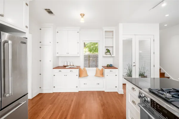a large white kitchen with a stove a refrigerator a sink dishwasher and white cabinets with wooden floor