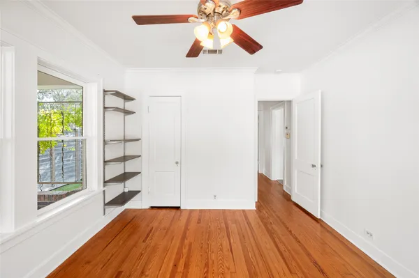 a view of empty room with wooden floor and fan
