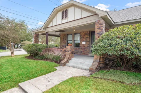 a front view of a house with a yard and potted plants