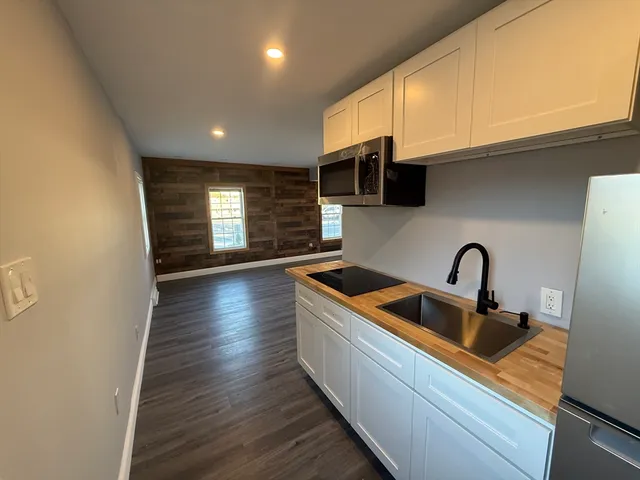 a kitchen with stainless steel appliances granite countertop a sink a stove and a wooden floors