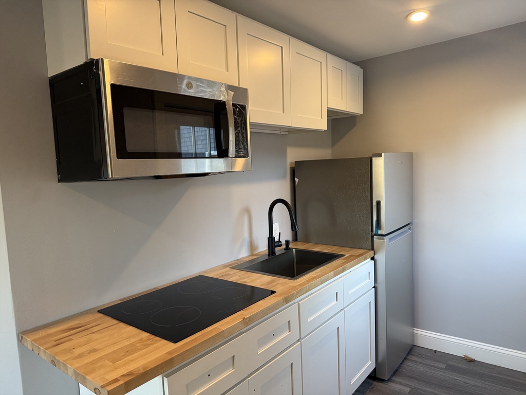176 Court Street, Unit 1 Plymouth, MA 02360 - Photo 2 of 11 a kitchen with stainless steel appliances a microwave a sink and cabinets