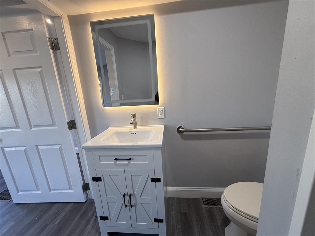 176 Court Street, Unit 1 Plymouth, MA 02360 - Photo 8 of 11 a bathroom with a sink a toilet a mirror and vanity