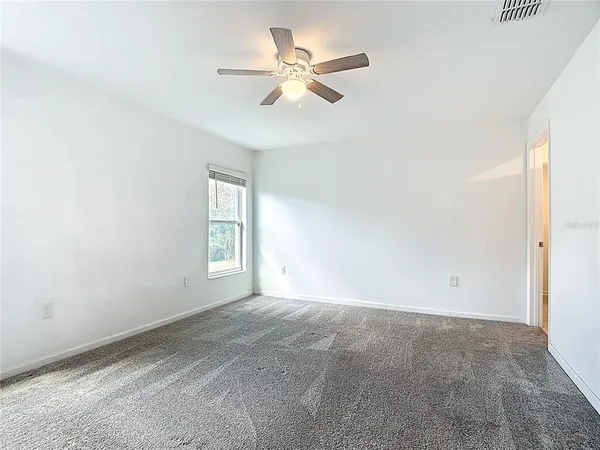 an empty room with a window and a ceiling fan