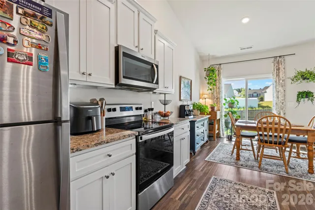 a kitchen with stainless steel appliances white cabinets and wooden floor
