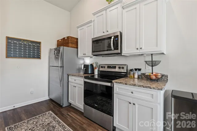 a kitchen with stainless steel appliances granite countertop a refrigerator stove and white cabinets