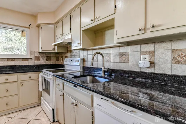 a kitchen with granite countertop a sink and a stove
