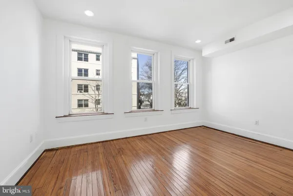 an empty room with wooden floor and windows