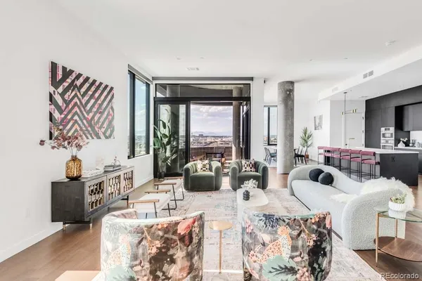 a living room with furniture large windows and wooden floor