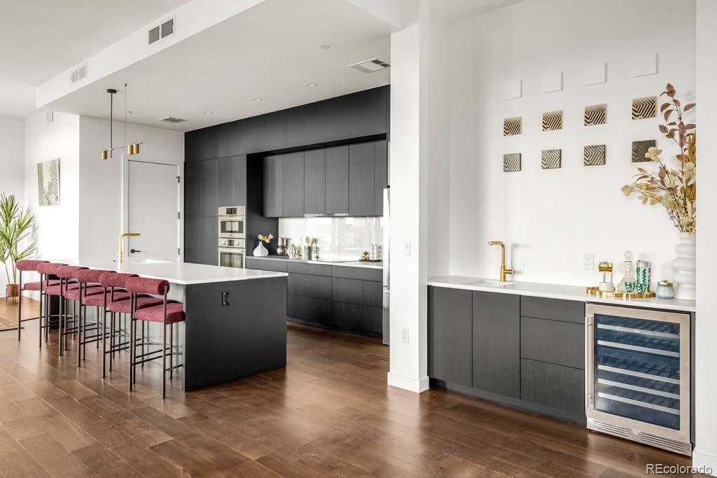 3520 Chestnut Place, Unit PH1201 Denver, CO 80216 - Photo 10 of 44 a kitchen with kitchen island a sink cabinets and wooden floor