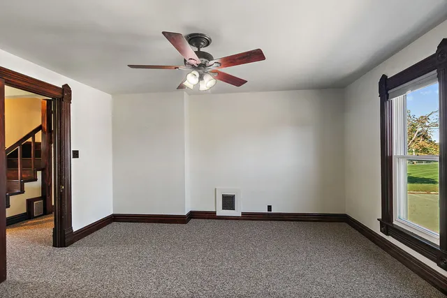 an empty room with windows and fan