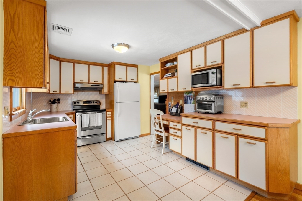 7 Belfast Road Peabody, MA 01960 - Photo 14 of 37 a kitchen with stainless steel appliances granite countertop a stove top oven a sink a refrigerator and white cabinets with wooden floor