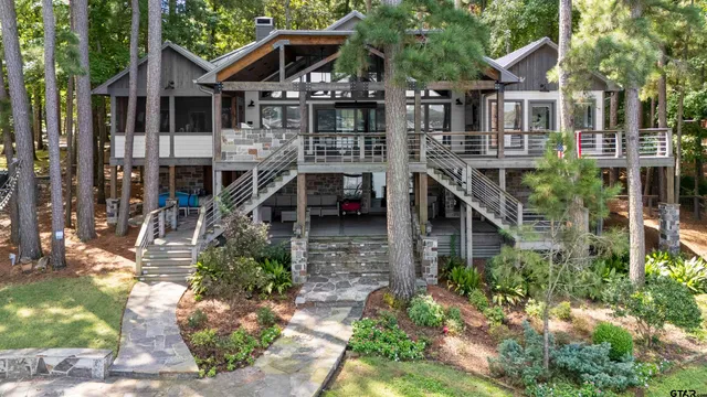 a living room with couches a fireplace and kitchen view with wooden floor