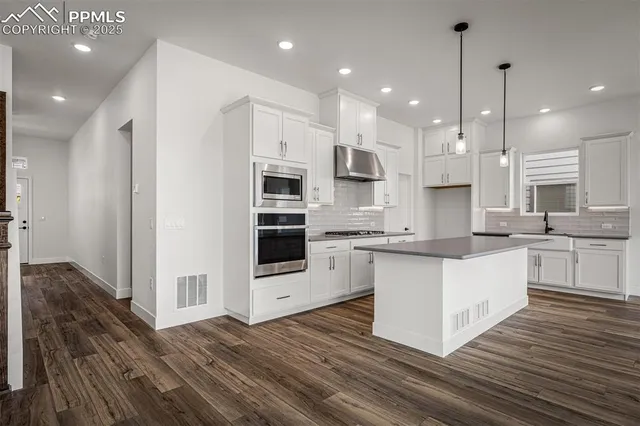 a large kitchen with kitchen island a sink stainless steel appliances and cabinets