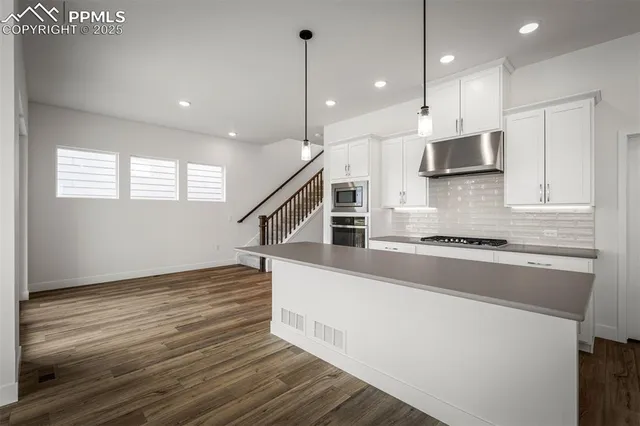a kitchen with stainless steel appliances granite countertop a stove a sink and a refrigerator
