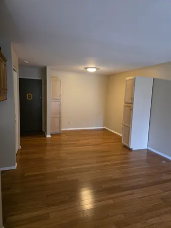 a view of an empty room with wooden floor and closet