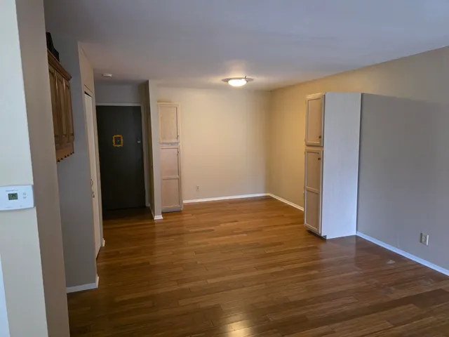 a view of an empty room with wooden floor and closet