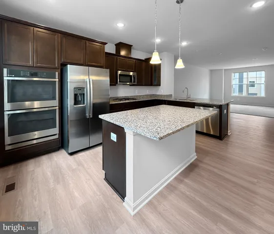 a kitchen with stainless steel appliances granite countertop a sink a oven and a refrigerator