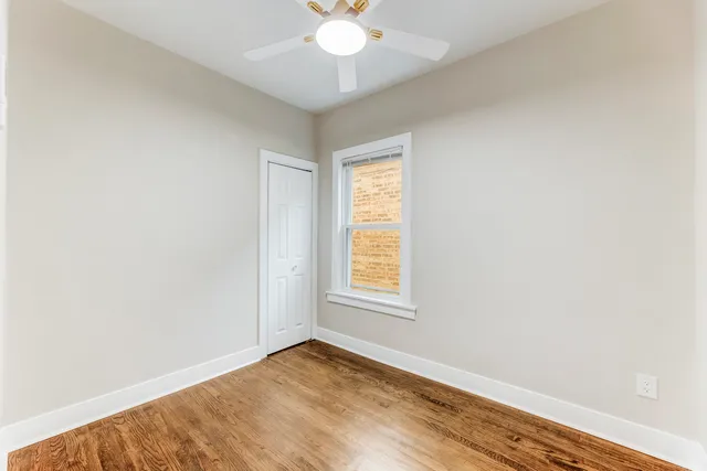 an empty room with window and chandelier fan