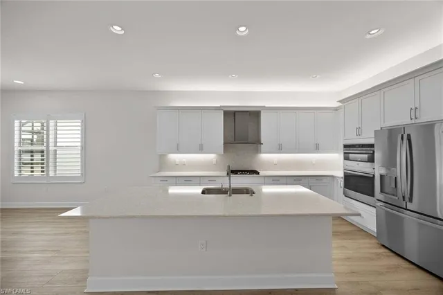 a living room with stainless steel appliances furniture a kitchen view and a window