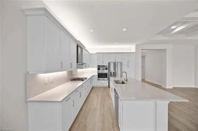 a large white kitchen with sink and a refrigerator