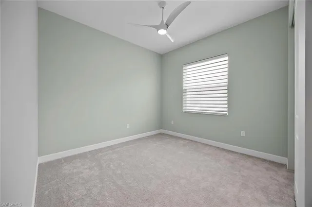 an empty room with a window and a ceiling fan