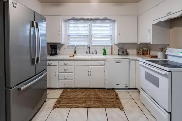 a kitchen with white cabinets appliances and a window