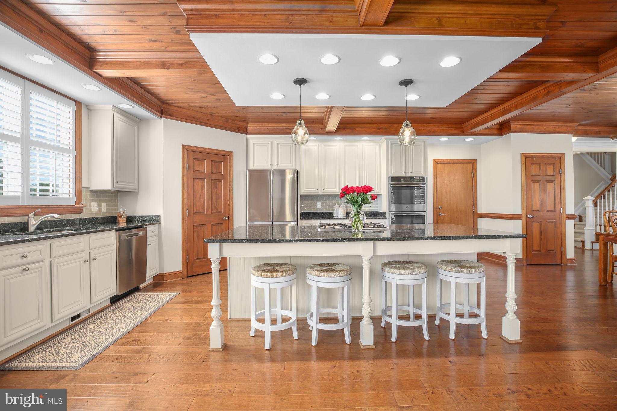 9910 Agnes Lane Spotsylvania, VA 22553 - Photo 23 of 106 a kitchen with stainless steel appliances granite countertop a stove top oven a sink a dining table and chairs with wooden floor