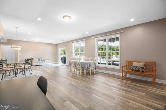 a kitchen with stainless steel appliances granite countertop a stove top oven a sink a dining table and chairs with wooden floor