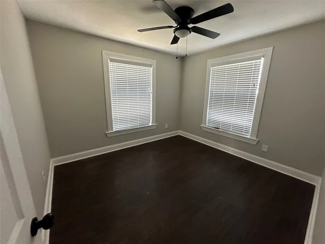 a view of an empty room with a window and wooden floor