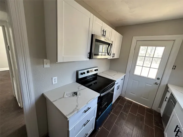 a kitchen with white cabinets sink and appliances