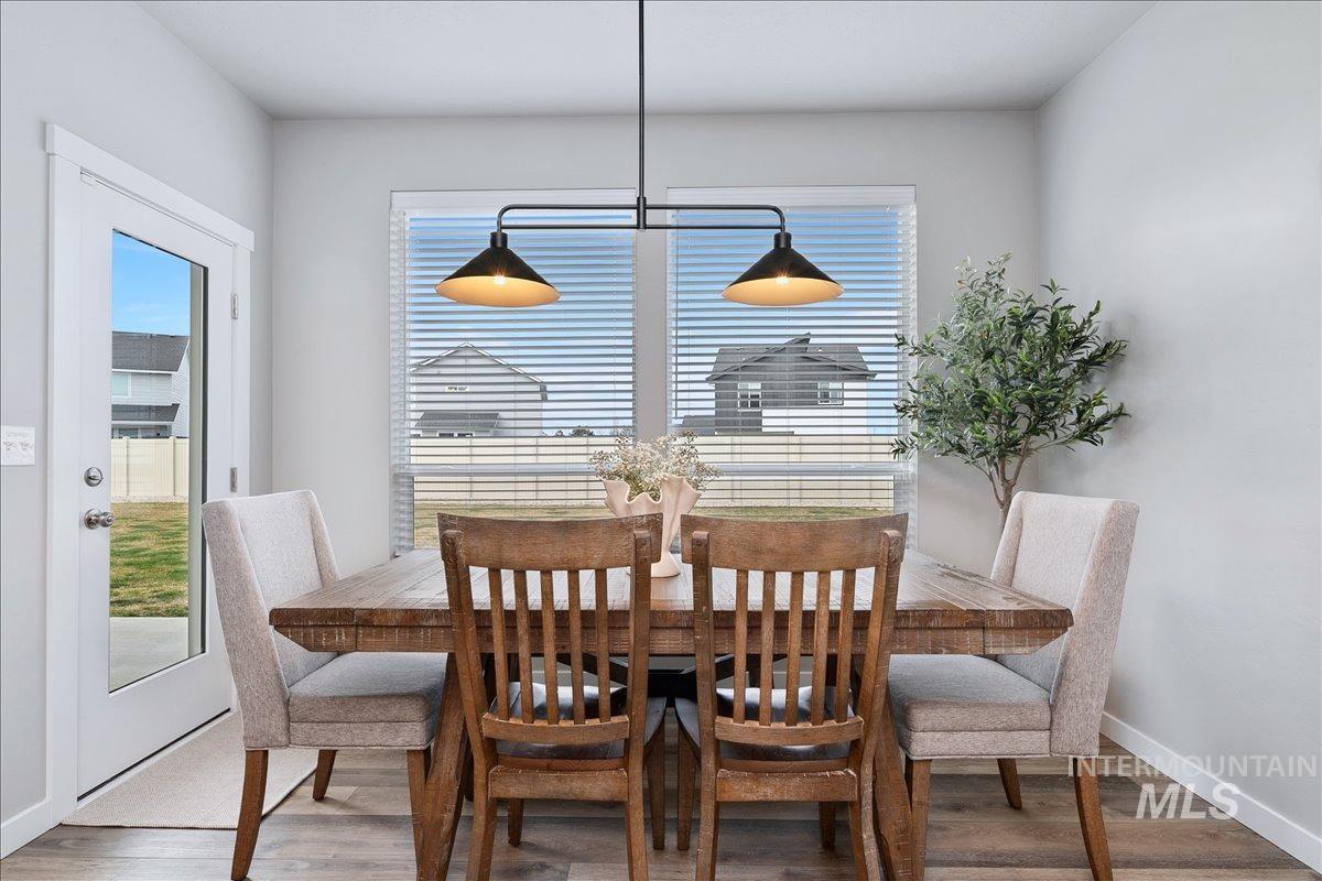 4215 North Pindus Avenue Meridian, ID 83646 - Photo 12 of 46 Dining room featuring LVP and picture window. Access to covered back patio and large back yard