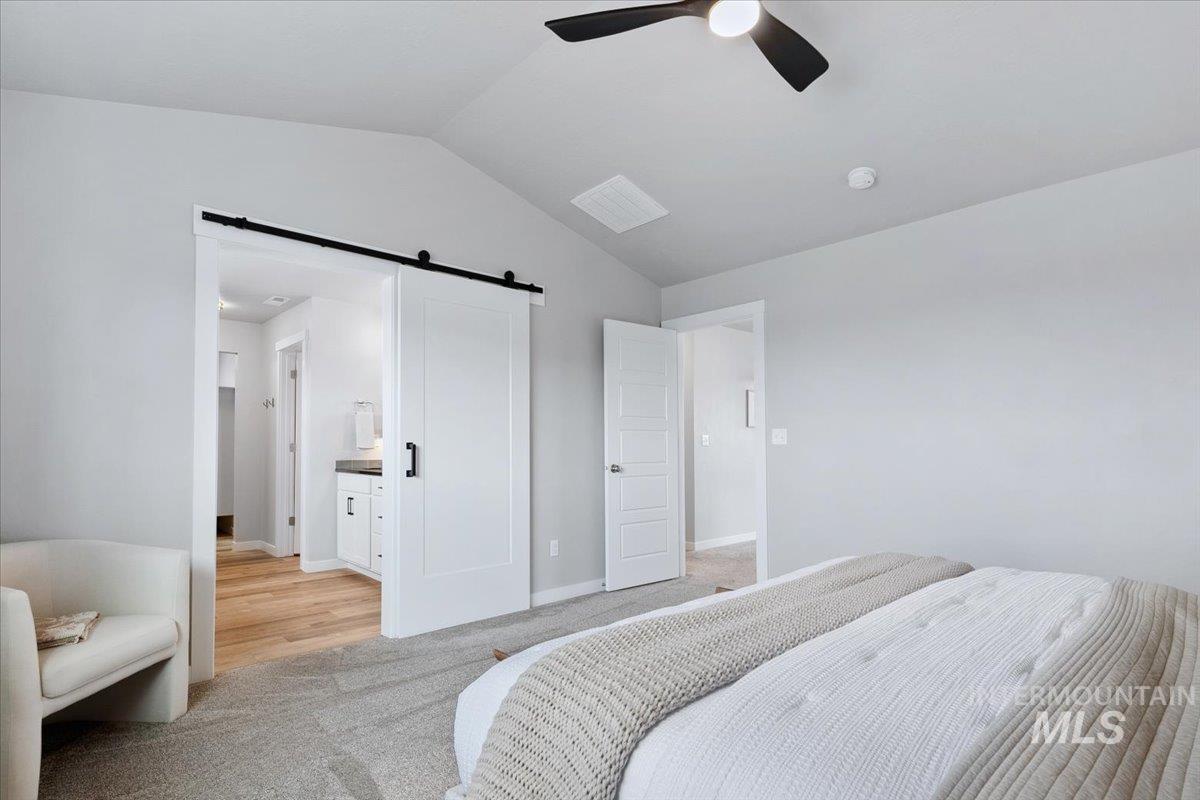 4215 North Pindus Avenue Meridian, ID 83646 - Photo 25 of 46 Bedroom featuring lofted ceiling, light colored carpet, ensuite bath, a barn door, and ceiling fan
