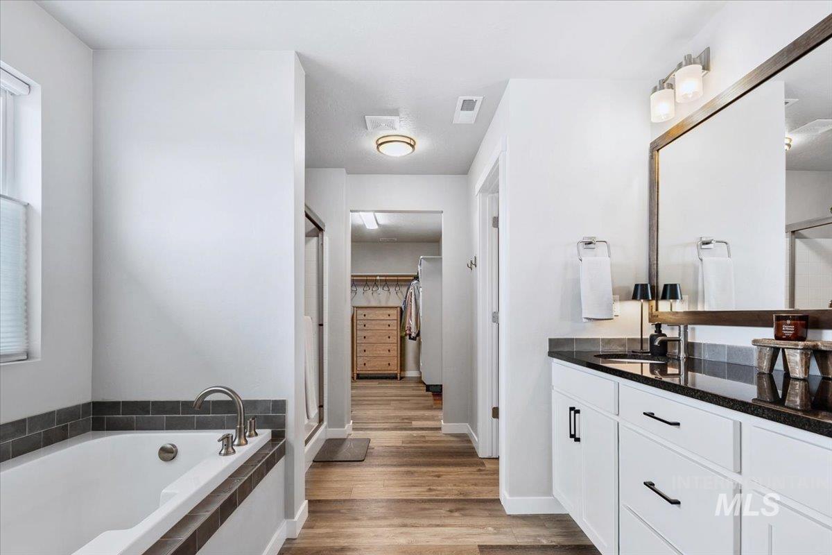 4215 North Pindus Avenue Meridian, ID 83646 - Photo 27 of 46 Bathroom featuring dual vanity, a soaker tub, window and a walk-in closet