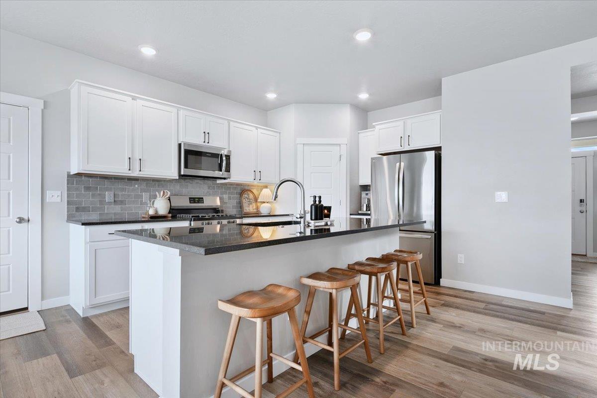 4215 North Pindus Avenue Meridian, ID 83646 - Photo 8 of 46 Kitchen with stainless steel appliances, white cabinets, a kitchen bar, LVP flooring, and recessed lighting
