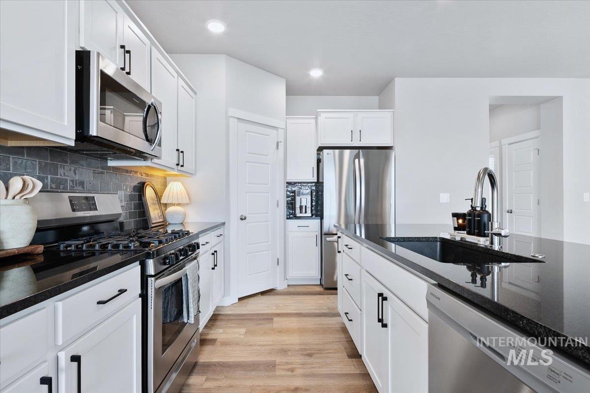 4215 North Pindus Avenue Meridian, ID 83646 - Photo 9 of 46 Kitchen featuring stainless steel appliances, dark quartz countertops, LVP floors, white cabinetry, and recessed lighting