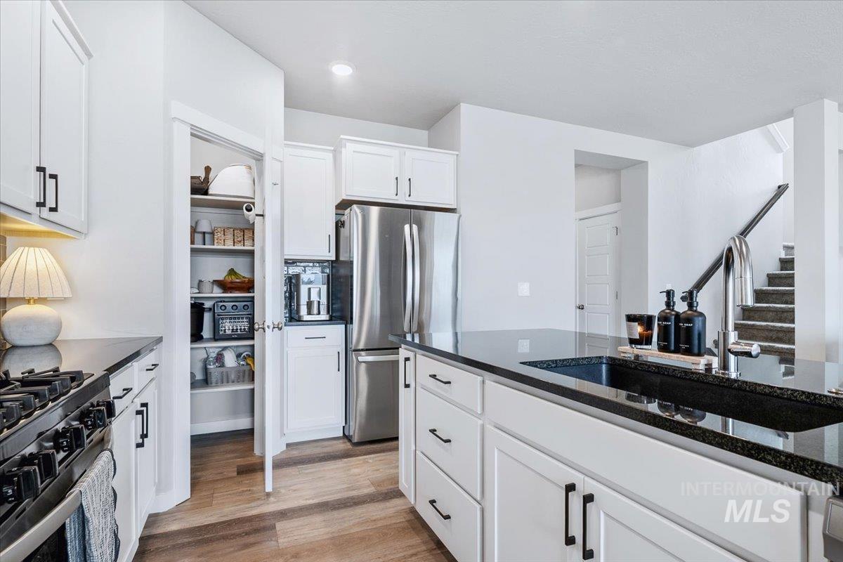 4215 North Pindus Avenue Meridian, ID 83646 - Photo 10 of 46 Kitchen with dark stone counters, stainless steel appliances, white cabinets, and light wood-style floors