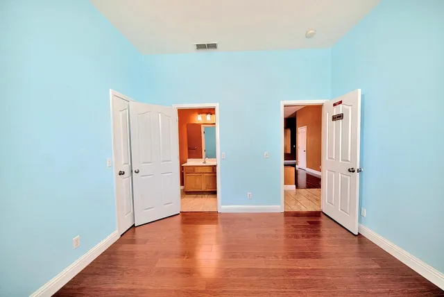 a view of an empty room with wooden floor and closet