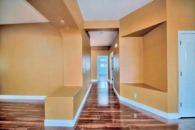 a view of a hallway with wooden floor and staircase