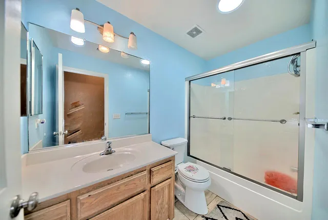 a bathroom with a sink a toilet a mirror and shower