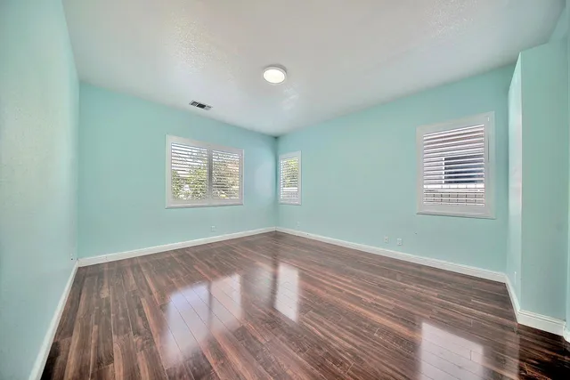 an empty room with wooden floor and windows