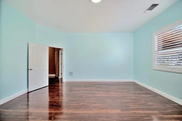 a view of an empty room with wooden floor and a window