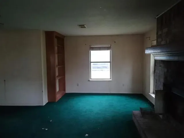 an empty room with a fireplace and a window