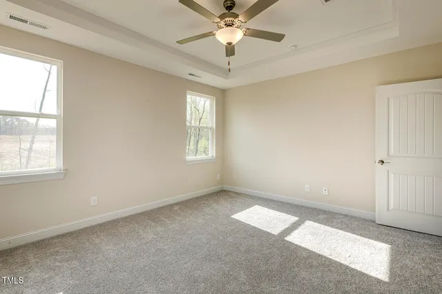 a view of empty room with window and chandelier fan