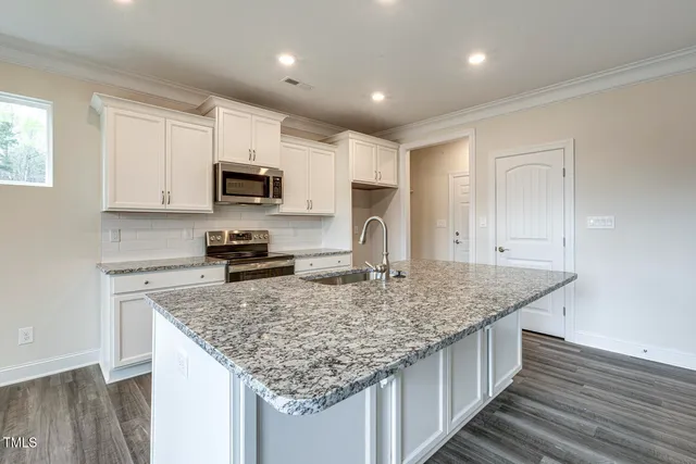 a kitchen with stainless steel appliances granite countertop a sink dishwasher stove and refrigerator with wooden floor