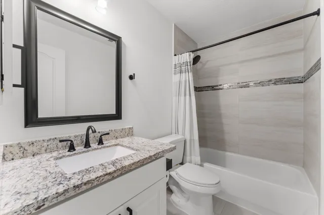 a bathroom with a granite countertop sink toilet and shower
