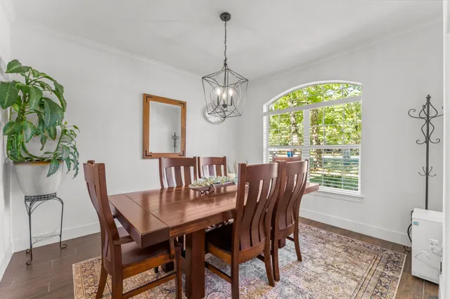 a dining room with furniture a rug a chandelier and a window