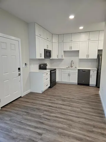 a large kitchen with cabinets wooden floor and stainless steel appliances