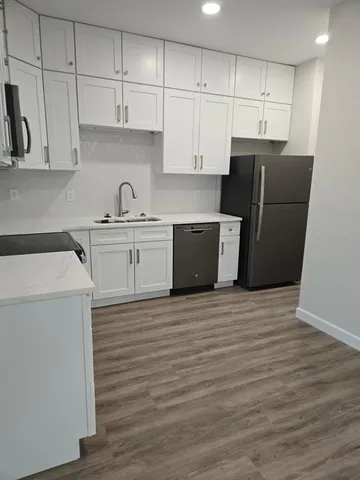 a kitchen with stainless steel appliances granite countertop a refrigerator sink and white cabinets