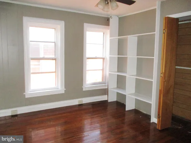 a view of an empty room with a window and wooden floor