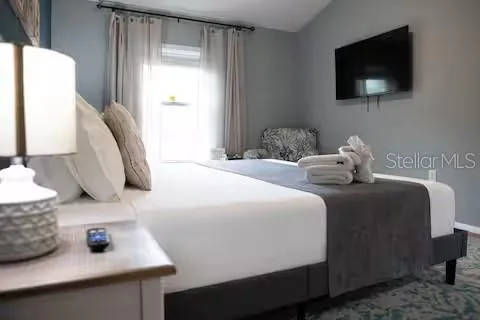 a bedroom with a bed a flat screen tv and window